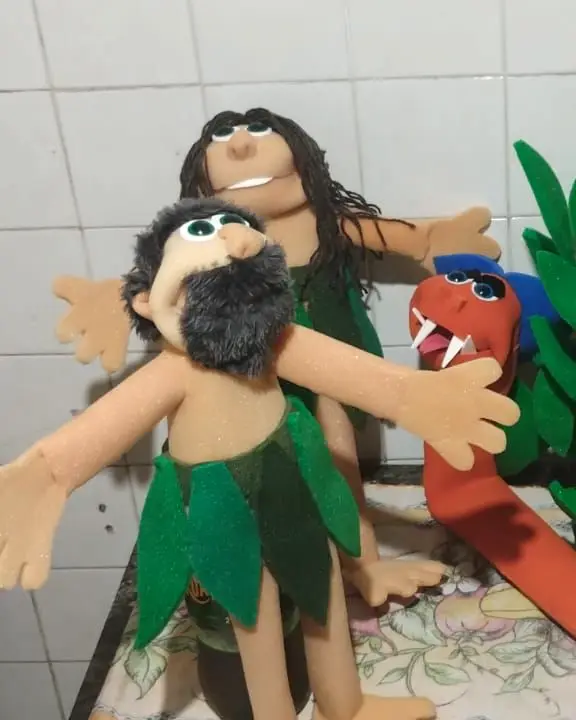 Adão, fantoche de barba escura e saia de folhas verdes