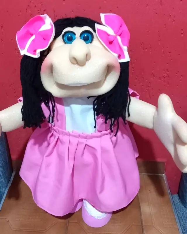 Boneca de cabelo preto com laços rosa e vestido rosa